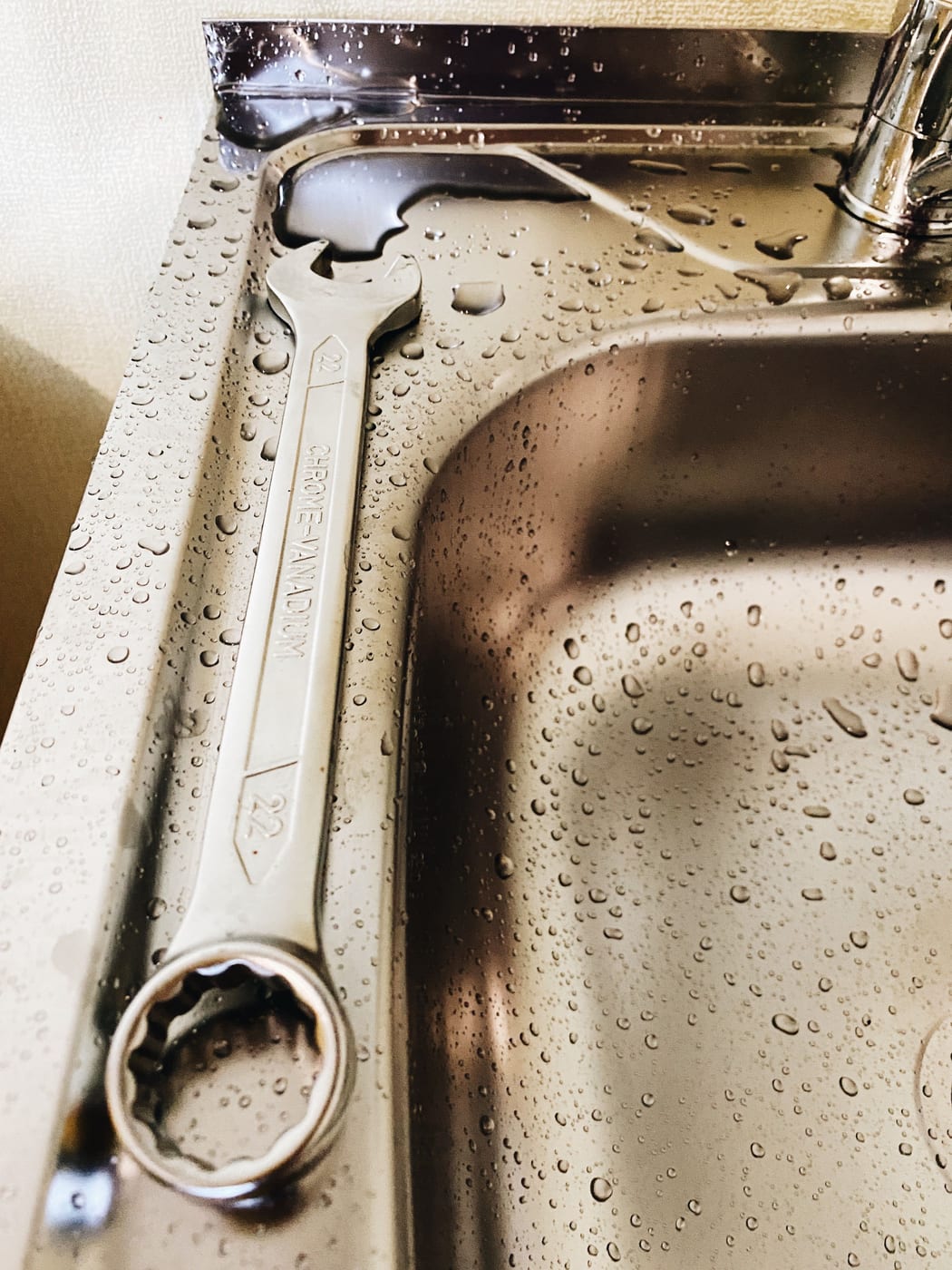 Rohrzange des Rohrreinigers am Rand eines Spülbeckens mit Wassertropfen auf dem Edelstahl
